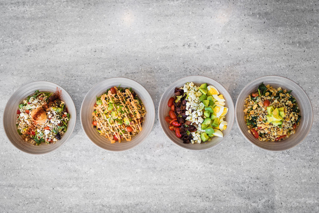 Four CRACK’D salads in bowls with fresh ingredients.